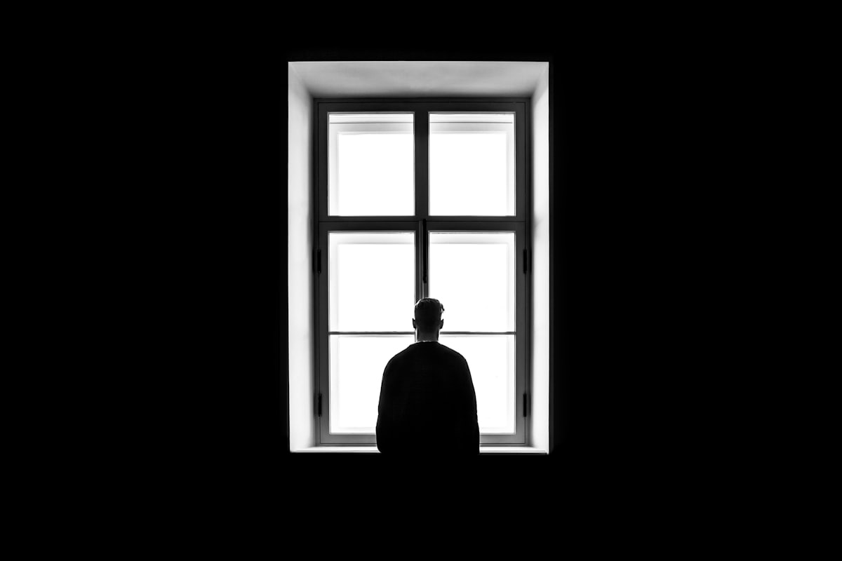 Nachdenkliche Person sitzt ruhig am Fenster